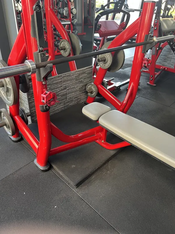 A red bench press station with a loaded barbell