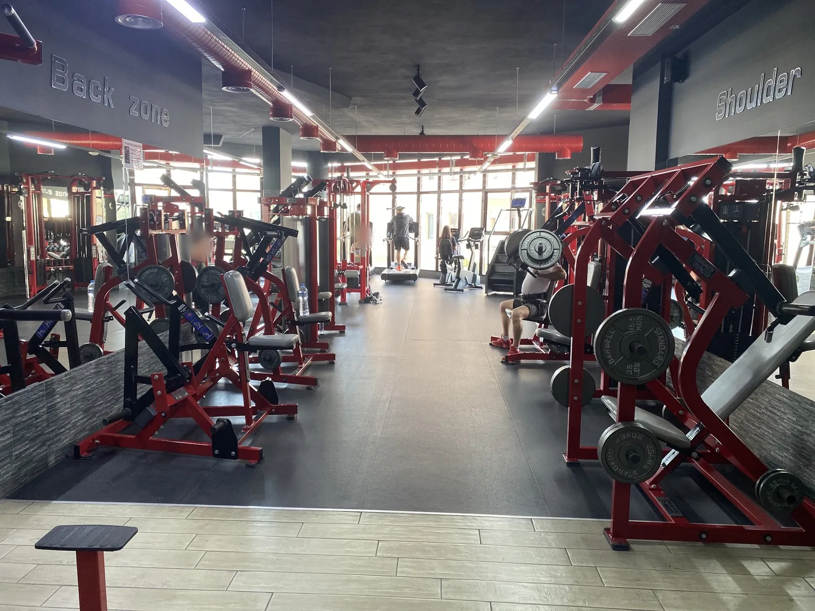 The Golden Gym training floor with rows of red plate-loaded machines under the Back zone and Shoulder signs